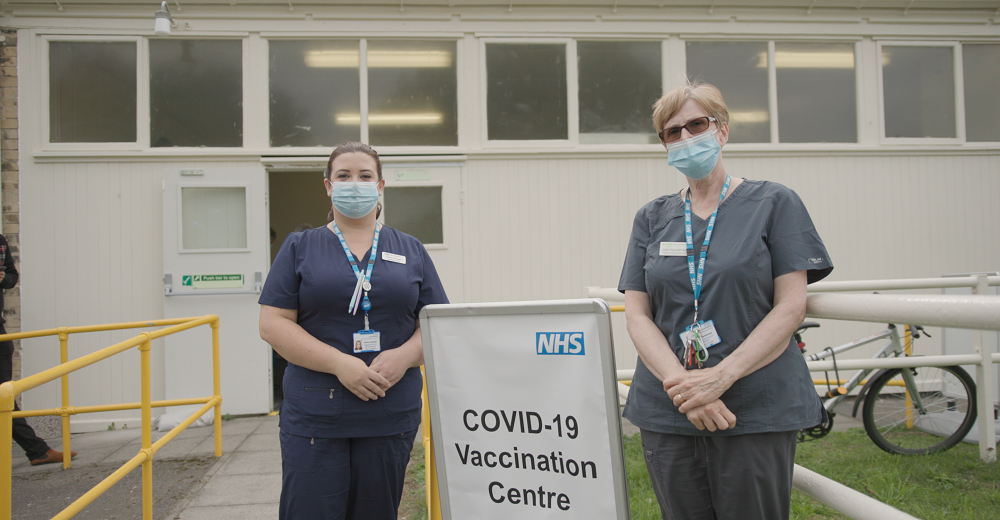 Two female vaccination team members standing outside vaccination centre