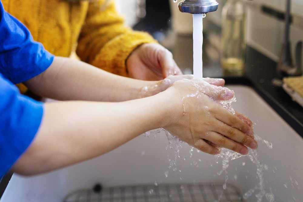 child washing their hands at a sink