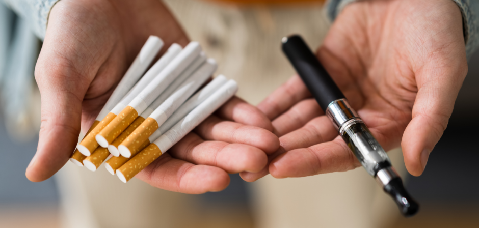 Image of a person with their hands open, left hand with a pile of cigarettes and right hand with a vape