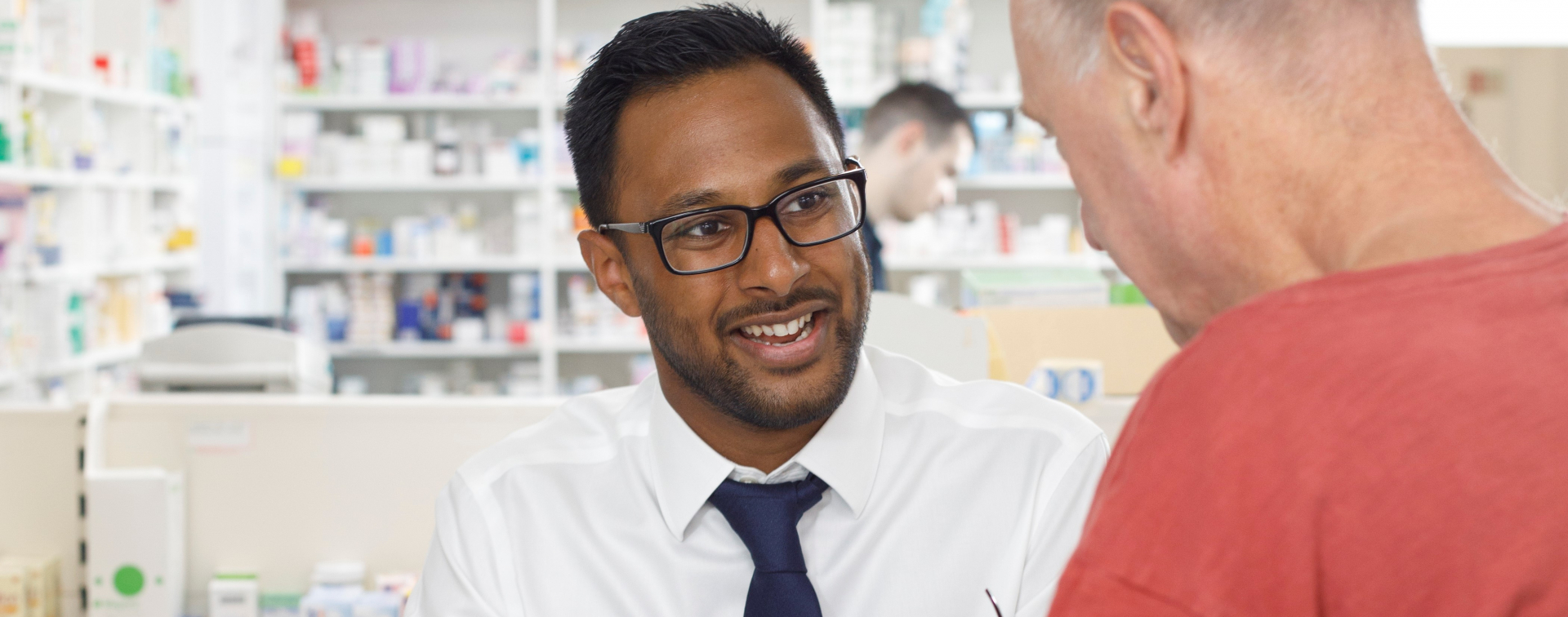 Male pharmacist speaking with a male customer