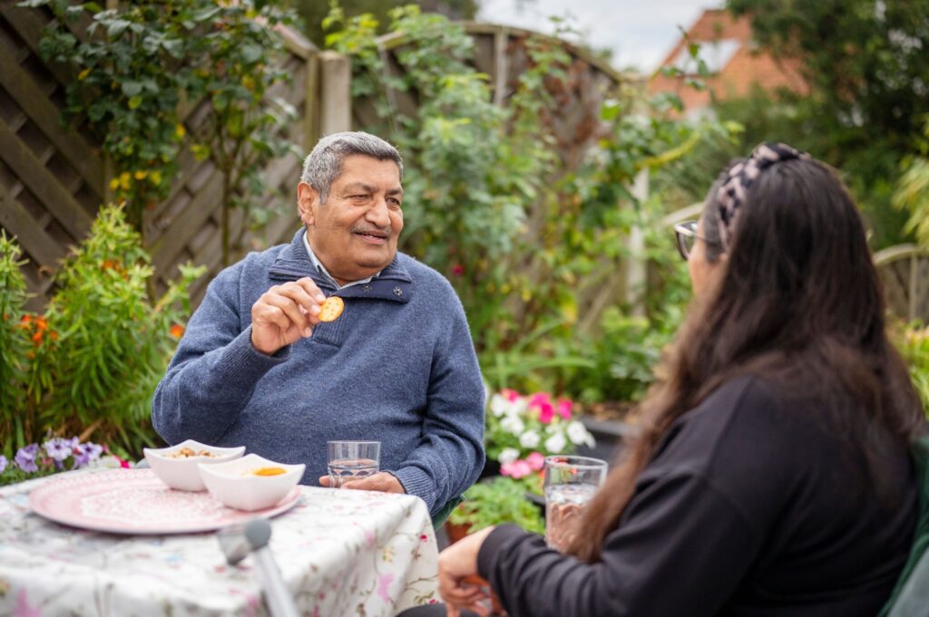 Older man sitting at a table talking to a woman