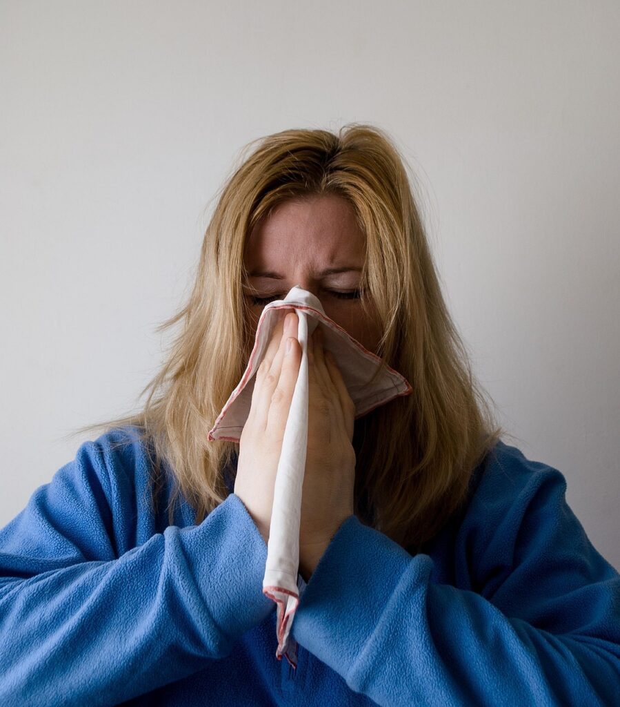 Woman blowing her nose due to allergy symptoms.