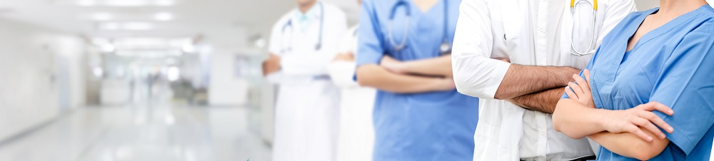 Close-up of diverse medical professionals standing with arms crossed in a bright hospital corridor.