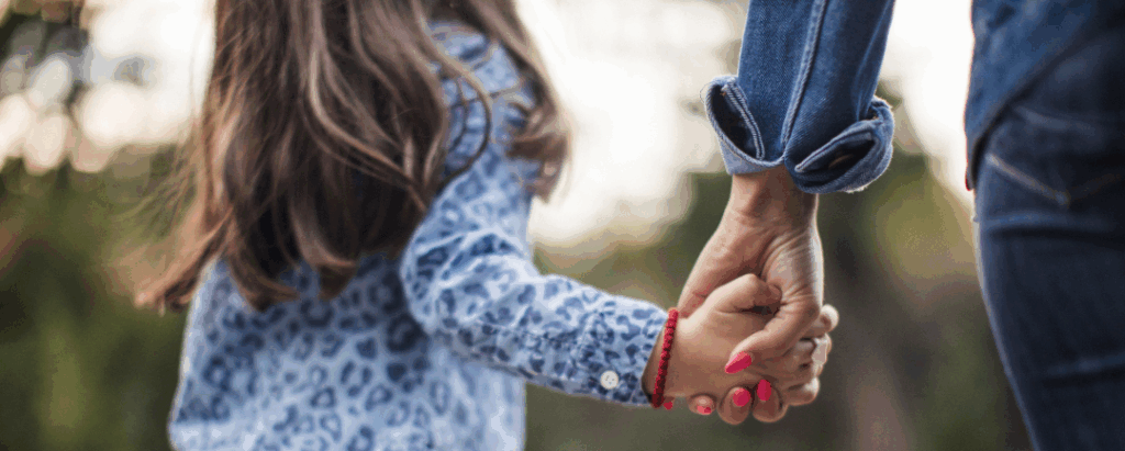 A child and a adult walking and holding hands