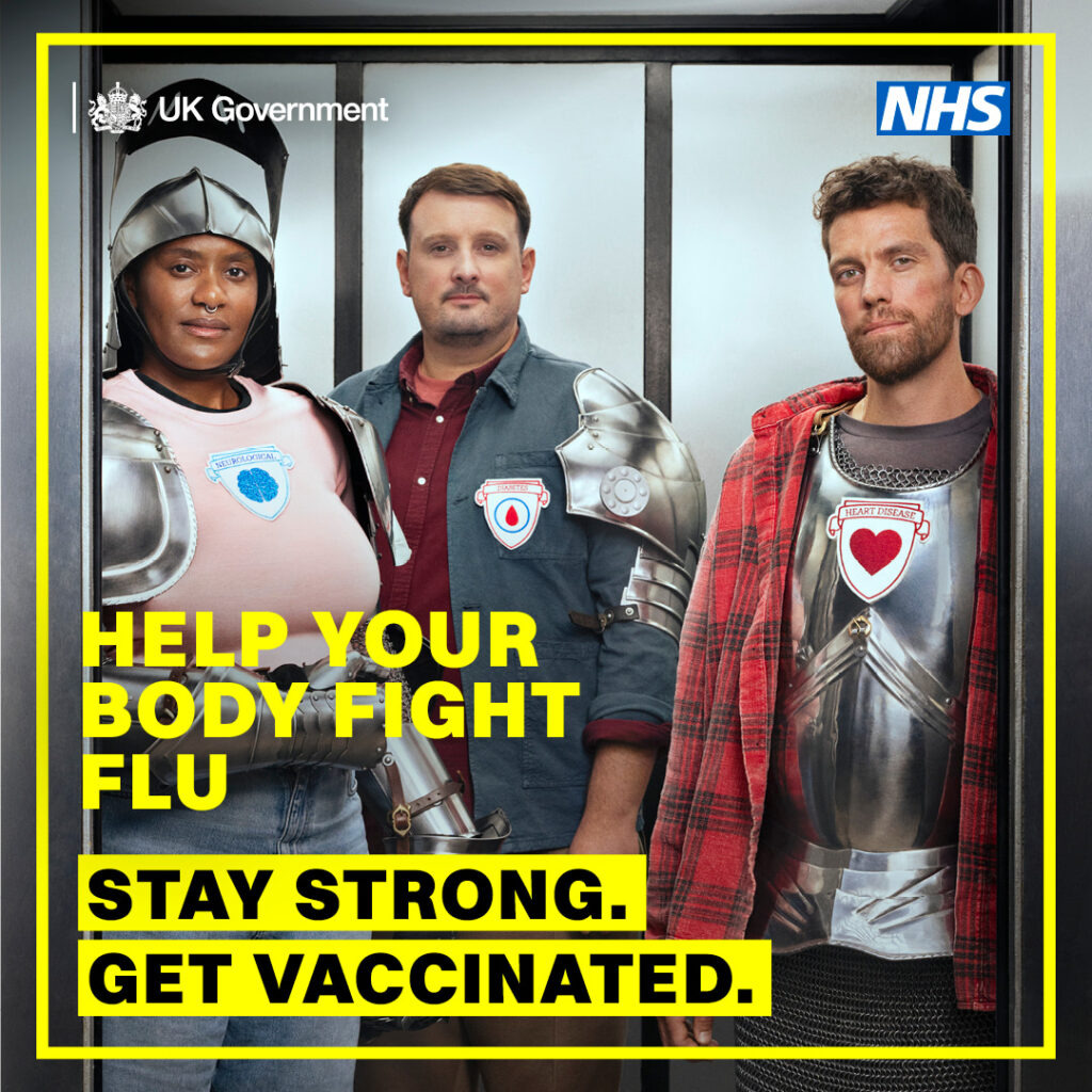 Three people wearing medieval armour over casual clothes stand together promoting flu vaccination by the UK Government and NHS.