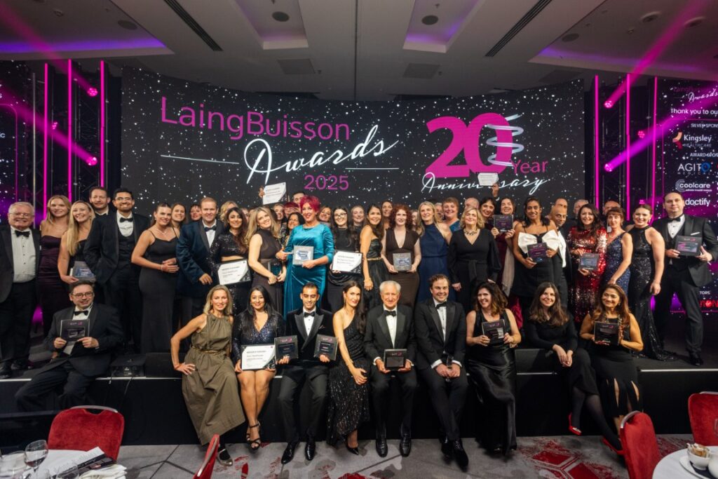 Group of formally dressed award winners posing on stage at LaingBuisson Awards 2025 celebrating 20 years anniversary.
