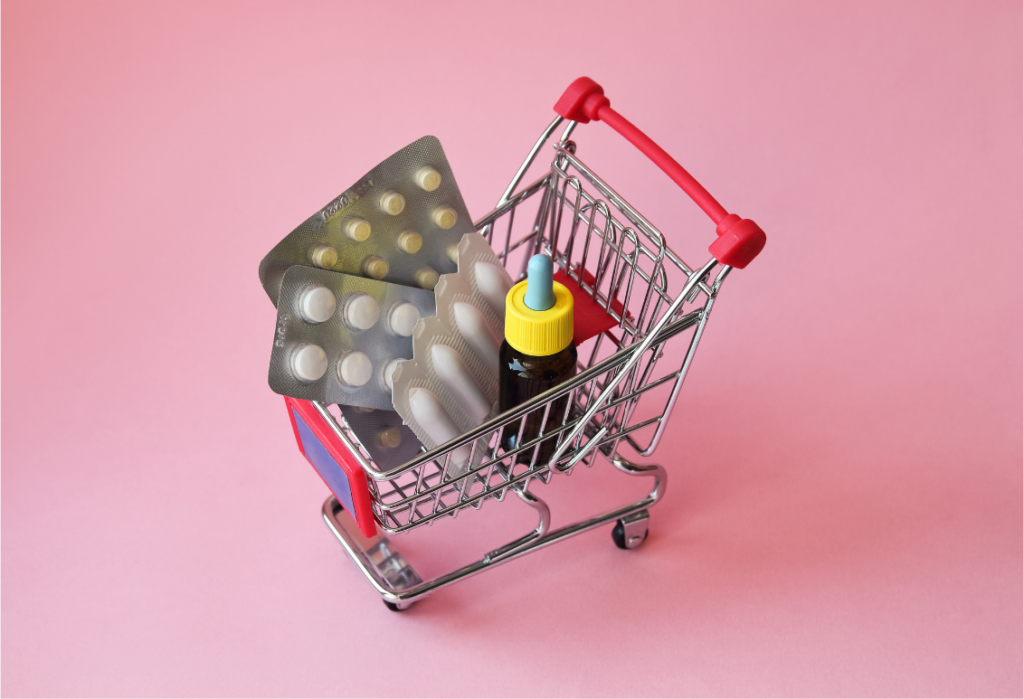 Photograph of a mini trolley on a pink surface that contains home medicines normally found in your medicine cabinet
