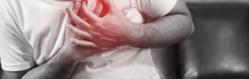 Man clutching his chest in pain, indicating possible heart discomfort.