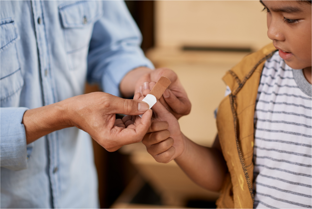 Photograph of a father putting a plaster on his son's hand