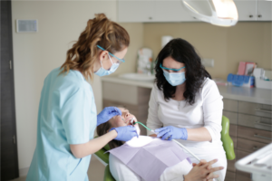 Photograph of two female dentists working on a female patient