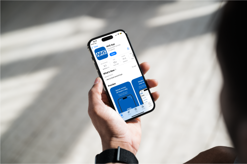 Photograph of a person holding a phone that shows the app store after the NHS app has been downloaded