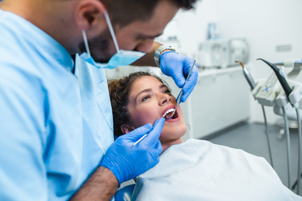 Photograph of a male dentist examining a female patients teeth