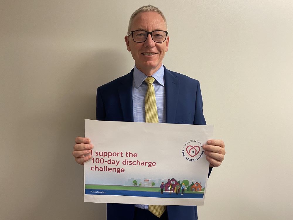 ULHT Chief Executive Andrew Morgan holding a sign saying "I support the 100 day discharge challenge"