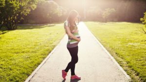 pregnant-woman-holding-her-belly-in-a-park-area