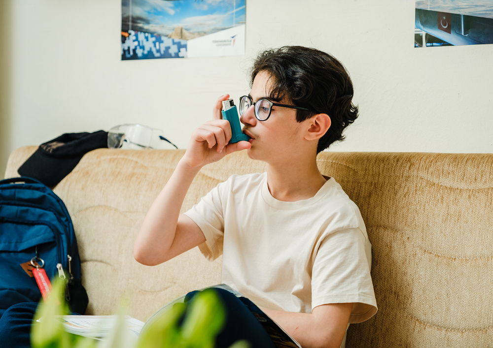 Young boy sat using an inhaler